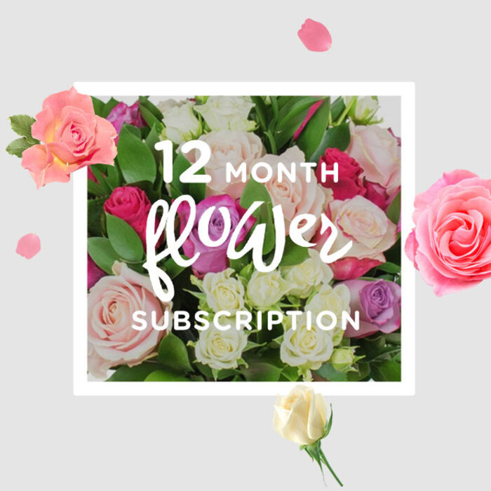 The photograph showcases a sumptuous arrangement of roses that embodies the quiet luxury of receiving flowers month after month. At the centre, a dense cluster of rose heads in blush, cream, soft lilac, and jewel-toned fuchsia nestle closely together, forming a rounded, almost cushion-like bouquet. Each bloom is captured at its own perfect moment: some roses are in early bud, hinting at promise, while others are fully open, their layered petals unfolding like small, intricate sculptures. The colours blend harmoniously, from champagne and powder-pink highlights to deeper raspberry and magenta accents, echoing the subtle shifts of light you might see over Mill Hill's gardens from morning to evening. Surrounding the roses, glossy green foliage offers a crisp contrast, adding both visual depth and a sense of fresh, living energy. Scattered petals and a few detached blossoms hover around the main arrangement, against a soft, creamy background that recalls the calm interior of a Mill Hill florist's studio or a bright sitting room near Mill Hill Broadway. This scattering feels like captured motion, as though the bouquet is in the midst of being arranged for another month's delivery in a 12-month flower subscription. You can almost inhale the bouquet's fragrance: a mix of sweet rose, slight spice, and green freshness, the kind of scent that gently fills a room without overwhelming it. The composition conveys a feeling of sustained care and ongoing celebration, suggesting how each new delivery across Mill Hill would bring a fresh chapter of beauty, from quiet weekday surprises to special occasions marked with roses that look and feel this exquisitely detailed.