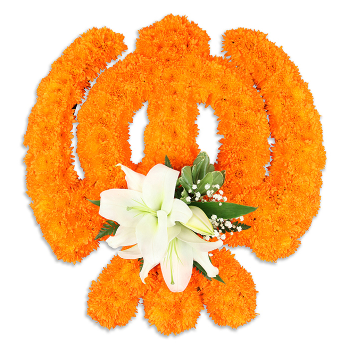 A luminous floral Ik Onkar rests on a pristine white surface, its curves and mark crafted with meticulous care from thousands of tiny bright orange marigold blooms. The sacred Sikh emblem that proclaims 'God is One' is rendered here with clear definition: the vertical Ek (numeral one) is shaped from dense marigold clusters, the flowing crescents and looping extensions carved with deliberate gaps to suggest line and movement, and the small dot or bindi finished as a concentrated blossom point. The orange marigolds create a warm, festival-like field, each little flower catching soft light and forming a tactile, low-relief texture. At the lower centre of the symbol a contrasting cluster of pristine white lilies has been artfully arranged; at least two lilies are open, their smooth petals curving outward to display delicate green-and-yellow stamens, while nearby buds promise further bloom. Fresh green foliage frames the lilies and threads the marigold structure, and fine sprays of tiny white gypsophila add a whisper of airiness that offsets the marigolds' density. A subtle cast shadow beneath the piece gives dimension and suggests a freestanding ceremonial plaque or tabletop offering. The overall feeling is devotional and unifying: bold celebratory orange tempered by serene white, suitable for Vaisakhi displays, Guru Nanak Jayanti adornments, or respectful home shrines. I can see this being brought to a gathering in Mill Hill Village or set near Dollis Brook for a quiet moment of devotion, the design speaking of craft, tradition, and gentle reverence.