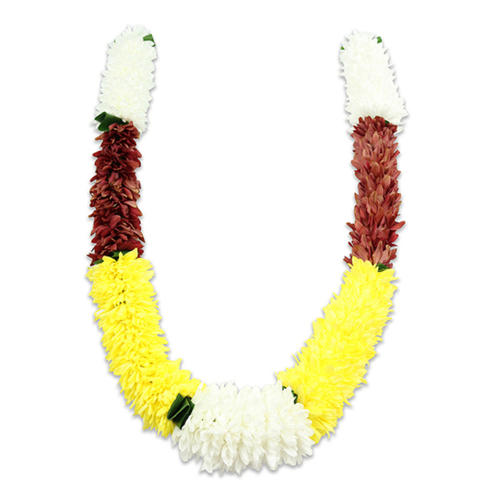 Set against a minimalist white field, this U-shaped floral garland presents itself with clear structure and emotive detail: compact white crowns at the very top of each arm, a rich maroon band beneath them, and a broad, effusive length of bright yellow forming the lower curve. The white sections-soft and chrysanthemum-like-are tightly packed into short, cylindrical segments that read as clean and auspicious. Directly beneath, the maroon or reddish-brown stage is composed of similarly dense, finely textured petals, grounding the colour story with an earthy, devotional tone. The yellow section flows extensively along each arm, its sunlit hue and plush density giving the garland a generous, welcoming sweep. Where the two yellow arms meet, a substantial cluster of pure white, chrysanthemum-style blooms creates the composition's focal heart, framed by small dark-green leaf accents that act as discreet separators between the colour fields. The garland's depth is enhanced by a faint shadow on the backdrop; the fabric petals-numbering in the thousands-are layered with artisanal precision so the piece reads full and uniform while retaining a handcrafted character. Intended for ceremonial use-pooja, temple offerings, weddings, or festive displays such as Diwali-the colour choices speak of purity, prosperity, and devotion. A Mill Hill florist preparing pieces for Bittacy Hill celebrations or a wedding at Mill Hill Village would appreciate how this durable, artificial mala combines tradition with longevity, offering a tactile, visual expression of respect and festivity that holds its shape and meaning through repeated use.