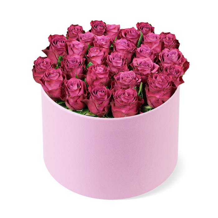 In this image, a pastel pink hat box filled with magenta roses stands alone against a bright white background, evoking the quiet luxury you might find in a well-kept Mill Hill home. The box is cylindrical, with straight sides and a perfectly flat top edge, finished in a soft, velvety matte texture that looks smooth to the touch and slightly muted under the studio lighting. From this delicate container rises a dense dome of roses, each bloom placed so closely beside its neighbour that they create a continuous, cushion-like surface of petals. The roses are a vivid deep fuchsia, verging on rich magenta, with subtle variations in tone caused by the way the light grazes their gently curled edges. The inner petals appear marginally lighter, almost glowing from within, while the outer petals deepen into luscious berry shades, suggesting freshness and fullness at the peak of bloom. Very little foliage is visible, just an occasional glimpse of dark green at the base of a bloom, which serves mainly to emphasise the richness of the pink tones by contrast. The arrangement is photographed from a slightly elevated position, as you might see it when standing beside a console table in a hallway near Mill Hill East, giving a clear view of both the domed top and the soft surface of the box. A subtle shadow beneath the arrangement grounds it, adding a sense of physical presence. The overall mood is romantic and celebratory, making this design ideal for same-day delivery to mark an engagement, an anniversary, or a special birthday in Mill Hill, from houses near Mill Hill Park to peaceful streets leading up towards Mill Hill Village.