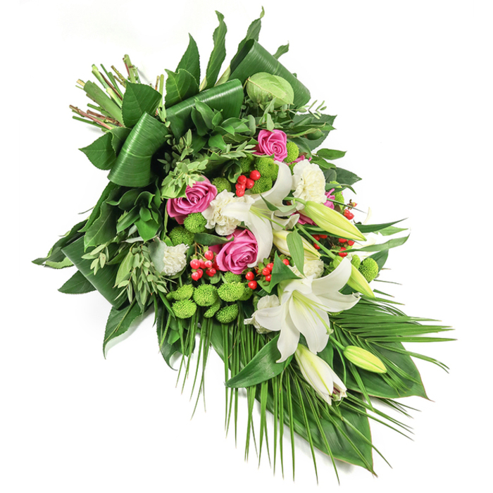 A touchstone of comfort and refined artistry, this elongated floral spray is crafted for Mill Hill's moments of remembrance. Laid diagonally across a pristine white background, the viewing journey begins with proud white oriental lilies-some blossoming fully, revealing slender golden stamens, while nearby, unopened buds promise delicate beauty to come. These are entwined with clusters of fuchsia and deep pink roses, spanning the stages from tightly held bud to gentle bloom, symbolising continuity and affection. Ruffled white spray carnations fill in spaces, softening the display and merging seamlessly with the surrounding palette. Contemporary energy arrives in the form of rounded, lime-green button chrysanthemums, their playful vibrance and mossy texture standing out amid the classic blooms. Scarlet red hypericum berries glimmer among an abundance of glossy, structured greens, including bold, folded leaves and fine-textured, eucalyptus-like sprays. The arrangement's long, palm-like fronds elegantly trail downwards, enhancing the flowing sense of movement and serenity. Lovingly designed by the team at Flowers Mill Hill, this tribute reflects both traditional sentiment and modern sophistication, making it a fitting arrangement for funerals, memorials, or condolence gestures delivered to families throughout Mill Hill, from The Ridgeway to Daws Lane.