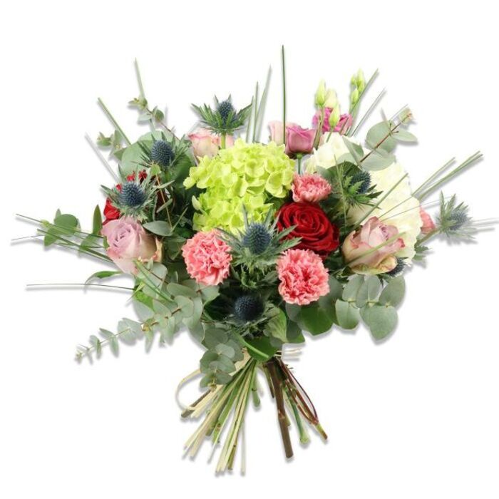 Presented against a crisp white field, this textured, hand-tied bouquet reads as both modern and timeless, crafted to reward close looking. At the visual centre is a voluminous lime-green hydrangea whose dense clusters of tiny florets form a soft, pillowy mass - the tactile anchor of the arrangement. Interspersed around it are tight, velvety red roses and softer blush pink and cream roses; some petals are still gently furled while others open into broader, more languid curves, providing a rhythm of form. Coral-pink carnations contribute generous ruffled layers, their frilly edges creating a pleasing contrast with the smoother rose faces. Multiple blue-grey Eryngium (sea holly) spikes introduce an architectural, almost metallic note: their spiny, star-like heads add a slightly wild, textural counterpoint that modernises the classic palette. The greenery is abundant and carefully chosen - silvery eucalyptus leaves with their aromatic, satin finish provide a cool, contemporary backdrop while long, upright blades of bright green grass add height and a sense of breeze. The bouquet's stems are visibly gathered and secured with a natural twine, the cut ends revealing fresh, green stalks and the handiwork of an experienced arranger. Bathed in soft natural light, this composition suggests a range of purposes - an intimate anniversary bouquet, a refined Mother's Day offering, or a fresh focal piece for a Mill Hill home near Bittacy Hill - radiating thoughtful colour, scent and craftsmanship.