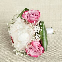 This charming bouquet captures the spirit of love and celebration, thoughtfully crafted by Flowers Mill Hill for local weddings, anniversaries, or heartfelt milestones. Nestled among the blooms, two majestic pink roses-each bloom unfurling from vivid magenta to blush and pale lavender-greet the eye with both vitality and grace. The centerpiece, a lush white peony in full bloom, reveals layer upon layer of delicate, ruffled petals, soft as silk and brimming with freshness akin to a stroll through Mill Hill's secret gardens after rain. Wisps of baby's breath, their minuscule white blossoms creating an airy, whimsical effect, swirl through the design, lending lightness and fairy-tale beauty. The arrangement is expertly encircled by broad, emerald-green leaves, their sheen and crisp edge providing structure, a nod to the verdant landscape of Mill Hill Fields. The slender stems are elegantly tied with a white satin ribbon, completing the bouquet's poised, hand-tied aesthetic. Positioned on a softly textured, beige linen backdrop, the bouquet's hues radiate against the subtle background, each detail illuminated by gentle, natural light. Ideal as a bridal or bridesmaid's bouquet or a joyful token for special occasions in Mill Hill, this piece exudes the warmth and artistry of local floral tradition, ensuring every celebration is touched by natural elegance.