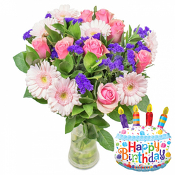 A plush birthday bouquet arranged with care, photographed in soft natural light that suggests early day deliveries across Mill Hill and the surrounding NW7 lanes. Dominating the view are dozens of soft pink roses, their petals rolling outward in layers from faint blush to richer pink, giving the arrangement a romantic, tactile presence. Nestled among those roses are generous pale pink Gerbera daisies, their broad petals forming bright halos with subtle yellow-green centers that catch the light. Throughout the mass of blooms, clusters of vivid purple filler-likely limonium or statice-create an architectural lacework of texture, the tiny papery flowers providing contrast and depth. Glossy deep-green foliage cushions and supports the flowers, its sheen and volume lending a garden-fresh backdrop. The bouquet sits in a clear, modest glass vase; the stems and clear water are visible below, a small honesty of freshness and florist craft. To the right, a whimsical metallic cake-shaped balloon punctuates the scene: a white frosted top edged with blue piping, scattered sprinkles in red, yellow, blue and green, and four striped candles-purple, red, orange and blue-each with a yellow flame. The phrase "Happy Birthday" runs across the front in playful multicolored letters, and the tiny logo "KALEIDOSCOPE" sits at the bottom rim of the balloon. As a Mill Hill florist I see this arrangement-suitable for collection near Mill Hill Broadway or arranged for local delivery-as a balanced birthday gift that blends classic floristry with a bright celebratory accent. Flowers Mill Hill can recreate this exact pairing for neighbourhood celebrations with careful attention to scent, proportion and freshness.