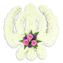 A beautifully composed Sikh Khanda funeral tribute takes centre stage, its strong, symbolic shape crafted wholly from flowers and framed by a pure white background. The central sword, the encircling chakkar, and the two crossing kirpans are all paved in tight clusters of white chrysanthemums, their petals soft and slightly feathery to the eye. Because the blooms are placed so closely together, the surface looks almost like a single, sculpted piece rather than many individual stems, with subtle variations of white and cream adding depth and dimension. The curves of the chakkar and the sweeping blades are cleanly defined, making the Khanda immediately recognisable. Just where the kirpans meet at the base, a compact burst of colour forms the emotional heart of the design. Three medium-sized pink roses, their centres gently unfurling, are arranged together, suggesting tenderness, love, and remembrance. Dotted among them are smaller deep purple flowers that add a layer of quiet richness, like a soft, solemn chord in a piece of music. Surrounding this focal area, glossy green leaves and fern fronds extend tastefully, their shapes echoing a natural woodland feel. The lighting is even and calm, casting a light shadow that adds subtle depth without distracting from the tribute itself. It is easy to picture this arrangement being prepared in a Mill Hill flower shop, destined for a Sikh funeral or memorial gathering for families from Mill Hill East, Finchley, or around Mill Hill Park. The tribute is both spiritual and personal, reflecting deep respect, cultural understanding, and the gentle care given to every stem.