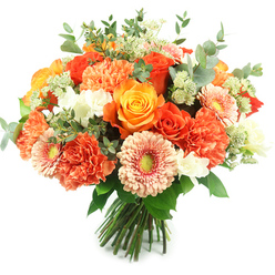 Bathed in gentle daylight, this hand-tied bouquet offers a concentrated moment of sunshine, arranged with the care of a Mill Hill florist and composed to read beautifully against a brilliant white background. The focal point is a cluster of large, fully opened roses in a spectrum of warm hues-from deep tangerine to bright golden-yellow-their spiralled petals forming intimate, aromatic cups. Interspersed among them are voluminous coral and peach carnations whose frilly, layered petals create a soft, tactile cushion that contrasts with the roses' sleek surfaces. Gerbera daisies bring a playful geometry to the design: flat, radiating petals in apricot and soft orange with vivid greenish centers that draw the eye inward. Sprays of tiny white blossoms-reminiscent of freesia or small spray carnations-offer crisp highlights while delicate, astrantia-like green clusters add a feathery, garden-fresh texture. Rounded eucalyptus leaves with their muted, silvery green tone are threaded throughout, releasing a cool, resinous scent that complements the sweeter floral notes. The stems are gathered and tied by hand, the tidy base suggesting freshness and readiness for immediate display on a dining table or to be delivered across Mill Hill, Mill Hill Broadway, or to neighbours near Bittacy Rise. As a local arrangement available from Flowers Mill Hill, it's ideal for birthdays, thank-you gestures, or anniversaries-an eloquent combination of warmth, texture, and considered floral craftsmanship designed to brighten homes and celebrate moments in our community.