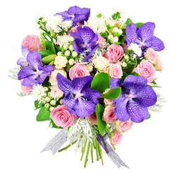 Photographed against a clean white backdrop, this luxurious bouquet appears almost luminous, each bloom carefully placed to create a harmonious, modern design. Dominating the arrangement are several striking Vanda orchids, their wide petals coloured in deep purple and blue tones, intricately speckled to form natural patterns that immediately draw the eye. These exotic flowers are embraced by soft pink roses, some just beginning to open, others fully unfurled, revealing layered, velvety petals that soften the overall look with gentle romance. Creamy white spray roses are scattered throughout, building volume and adding a warm, ivory glow. Tucked between the larger flowers are petite white filler blossoms and white hypericum berries, their polished, bead-like shapes adding tactile interest. Wisps of feathery dusted foliage-likely dusty miller-thread through the bouquet in subtle shades of silvery grey, cooling the colour palette and bringing a touch of softness, while rich, glossy green leaves form a lush, structured base. The stems are tied into a rounded, compact shape and finished with a semi-sheer ribbon that shimmers in silver and lilac tones, echoing the cooler hues of the orchids. The bouquet feels perfectly suited to Mill Hill life-imagine it gracing a dining table after a walk on Arrandene Open Space, or brightening a living room near Mill Hill Broadway station. Its thoughtful mix of purple, pink, and white speaks of admiration, tenderness, and celebration, making it a beautiful choice for birthdays, engagements, or simply sending love within NW7. Every detail suggests the steady hand of a local florist, attentive to balance, colour harmony, and the emotional impact that fresh, premium flowers can bring.