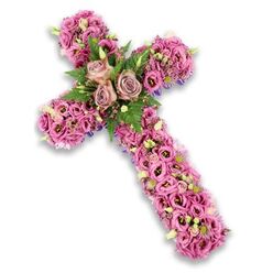 Set against a clean, bright white background, this floral cross seems to float, its structure rendered almost invisible beneath a lavish covering of blooms in pink, mauve, and gentle lavender tones. The arms of the cross are formed from densely packed lisianthus, their ruffled, cup-shaped petals overlapping one another, some showing darker centres that add a subtle, shadowed depth. At the very centre, where the vertical and horizontal elements meet, three striking roses become the heart of the tribute. These roses, in hushed dusty rose and light mauve hues, are fully open, revealing spirals of velvety petals that feel both timeless and contemporary. Around them, bright green fern fronds and smaller, leafy greens weave between the flowers, creating a fresh contrast that echoes an English garden after rain. Scattered through the lisianthus are clusters of tiny pink and purple filler flowers, alongside creamy white blossoms and pale green buds that softly break up the pastel sweep with touches of texture. Along the outer contours of the cross, fine hints of a darker purple ribbon or structural fabric can be glimpsed beneath the flowers, subtly reinforcing the shape without drawing attention away from the blooms themselves. The overall impression is one of composed reverence and gentle comfort, the cross a floral expression of faith and love. It feels perfectly suited to a Mill Hill farewell, perhaps resting in a quiet chapel off Mill Hill Broadway or being carried into a memorial service overlooking the green spaces near Mill Hill Park, offering solace through its delicate, beautifully arranged flowers.
