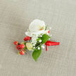 Laid gently on a neutral beige, subtly textured fabric that suggests linen or burlap, this boutonniere reads like a miniature still life painted with seasonal contrasts. The focal note is a pristine white phalaenopsis orchid, its wide, silky petals curling back to reveal a soft yellow-orange centre, delicate as cream tinged with sunlight. Encircling the orchid, the tiny, cloud-like blooms of gypsophila create an ethereal, frosted halo that softens edges and lends the composition a breathy, romantic quality. Scattered in small clusters, bright red hypericum berries create joyful punctuation; their smooth, glossy surfaces reflect the light and bring a rustic, celebratory energy reminiscent of berries picked from a hedgerow near Mill Hill Broadway. Pale green buds - slender and hopeful - suggest newness and quiet motion, while deep green salal leaves with their satiny finish provide a rich backdrop that enhances each colour contrast. The stems are fastened with a deep red satin ribbon tied into a discreet knot, the ribbon's tail angling slightly to the right and lending a handcrafted flourish. Under soft studio light, textures and tones are gently modelled so you can almost feel the orchid's velvet coolness and the ribbon's silky slide. Perfect for a groom or guest seeking subtle sophistication, this boutonniere carries the hush of a morning in Mill Hill Village and the assured touch of a local florist's hands, ready for a special day.