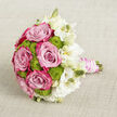 This image presents a hand-tied wedding bouquet resting on a pale beige, subtly textured cloth, the understated background reminiscent of a calm Mill Hill living room just before guests arrive. The bouquet is a considered blend of romantic pink roses, bright lime green button chrysanthemums, and soft white lisianthus, all gathered into a compact, rounded form. On the left and at the core, generous roses open fully, revealing spirals of petals that fade from soft, powdery pink at the centre into darker, more vibrant fuchsia and magenta tones at the tips. Their plush, velvety appearance gives a feeling of warmth and classic romance. Peeking between the roses, lime green button chrysanthemums form small, perfectly rounded clusters, their fine, densely packed florets adding a tactile, bumpy texture that brings life and freshness, much like the lawns and hedges around Mill Hill Park after a spring shower. To the right, a veil of white lisianthus blooms and long, slender buds stretches outward, the petals gently ruffled and slightly translucent, shifting from creamy white to shining ivory. These lighter tones create a soft halo that balances and frames the richer colours. The stems have been precisely cut and aligned, then wrapped into an easy-to-hold handle with blush pink satin ribbon, which is further adorned by winding strands of white pearls, echoing the detail of a bride's jewellery or beaded veil. The arrangement feels poised and serene, evoking the quiet anticipation before a ceremony at a Mill Hill church or registry office, when every flower is fresh and every detail has been thoughtfully considered.