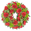 A classic circular wreath for funerals and memorial services is captured against a stark white background, which throws its rich colours and textures into sharp relief. The ring is fully covered with flowers and foliage, creating a dense, substantial look that communicates care and attention to detail. Most prominent are the deep red carnations, their many, finely ruffled petals forming soft, rounded blooms that are repeated all around the circle. Their crimson shade is strong yet gentle, suggesting enduring love and respect. Tucked between these red blossoms are bright lime green button chrysanthemums, compact and spherical, each one like a small cushion formed from tiny, tightly arranged petals. Their crisp green hue provides a refreshing contrast to the deeper reds, bringing an element of brightness that prevents the wreath from feeling sombre. The flowers sit on a foundation of mixed greenery: dark green, feathery fern fronds add depth, while variegated leaves with creamy margins lighten and soften the overall effect. Subtle loops of striped green ribbon weave through the foliage, echoing the tones of the button mums and adding a quiet decorative touch crafted in the style of local Mill Hill florists. The wreath's circle appears perfectly even, with no side feeling heavier than another, conveying a sense of balance and completion. Imagined resting at a chapel near Mill Hill Broadway, by a graveside, or within a family home during a wake, this wreath would serve as a visual expression of condolence, remembrance, and the continuity of love even after loss.