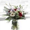 This Mill Hill bouquet encapsulates a poetic blend of harmony and softness. At the core, velvety red roses radiate passion, surrounded by creamy white gerberas dotted with striking brown centres-together echoing the tranquillity of Mill Hill's green open spaces. Gentle, pale lilac lisianthus blooms and buds are threaded throughout, signaling new possibilities. Dainty white filler flowers cluster like delicate clouds, their light texture brightening the whole. Arcing gracefully around the display, eucalyptus branches offer a cool, silvery-green backdrop and a hint of invigorating scent reminiscent of the fresh Mill Hill air. Structural leaves, polished and deep green, cradle the bouquet like a protective embrace, all nestled in a crystal-clear glass vase with freshly cut stems submerged in water. Perfect for expressing gratitude or celebrating milestones near Bittacy Hill, this arrangement reflects the care and artistry of Mill Hill's skilled local florists.