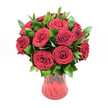 A lush, romantic bouquet of around twelve to fifteen deep crimson red roses is gathered tightly into a classic, rounded shape and presented in a translucent red glass vase, all set against a spotless white studio background that makes every detail stand out. Each rose is fully open, its velvety petals spiralling in perfect, intricate whorls that create a sense of movement and depth, as though the blooms are gently unfurling before your eyes. The rich, ruby tones of the petals are intense and saturated, with subtle variations of darker wine-red in the shadowed folds and softer, glowing scarlet where the light catches the outer edges. Cradling and framing the roses is an abundance of glossy dark green foliage, likely ruscus or a similar leaf, each leaf smooth, slightly pointed, and shining as if freshly misted. These leaves weave between the rose heads, adding contrast, fullness, and a natural rhythm that stops the arrangement feeling too rigid. The red glass vase curves softly from a narrower base up to a flared, generous opening, its ribbed or gently swirled texture catching the light so that the glass seems to shimmer with darker and lighter red currents. Though translucent, the vase looks richly coloured, as if it's been blown with layers of liquid ruby. The lighting is bright and even, much like a clear morning in Mill Hill, highlighting every petal edge and leaf vein without casting harsh shadows. This bouquet feels like a heartfelt declaration of love - the kind of arrangement a Mill Hill local might send to a partner in nearby Holders Hill or down at Mill Hill Broadway for an anniversary, Valentine's Day, or any moment when pure, unmistakable romance is the message.