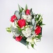 A lush hand-tied bouquet is captured from above, its colours glowing softly as if in gentle morning light over Mill Hill Broadway. At the heart of the arrangement, velvety red roses and vivid pink-red carnations cluster together, their ruffled and spiralling petals creating a rich, romantic focal point. Around them, small snow-white chrysanthemums and daisy-like blooms form a bright halo, their round faces and neatly layered petals bringing a fresh, innocent charm. Wisps of delicate gypsophila, or baby's breath, drift between the larger flowers like tiny clouds, adding an airy, almost weightless feel. Eucalyptus stems thread through the bouquet, their rounded, silvery-green leaves giving a cool, modern edge, while deeper tropical greenery frames the design with glossy, sculpted shapes. The overall structure is full yet breathable, each bloom given space to be seen, like neighbours chatting on a quiet Mill Hill side street. You can almost imagine the light herbal scent of eucalyptus mingling with the sweetness of rose and carnation, a fragrance that would gently fill a hallway or living room near Mill Hill Park. The colour palette balances bold reds and pinks with pure whites and fresh greens, evoking joy, affection, and the promise of celebration. It feels like a bouquet chosen to mark a happy return home from the Thameslink station, a birthday gathering around a kitchen table, or a surprise delivery to brighten a flat overlooking local gardens. Every petal and leaf reflects the careful eye of an experienced florist, intent on creating a bouquet that feels both uplifting and reassuring, like the start of a cherished new chapter.