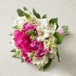This joyful hand-tied bouquet, set against a soft neutral background, radiates the best of Mill Hill's springtime spirit. Plump, hot pink peonies-each one bursting with layers of delicate, ruffled petals-form the luxurious core of the arrangement, bringing intense colour and an opulent tactile effect. They're highlighted by crisp white Alstroemeria blooms, their narrow petals marked by intricate maroon streaks, which contribute both brightness and gentle detail. Scattered amongst the larger florals, upright, spiky green florets-reminiscent of budding Veronica or Hyacinth-add a fresh, lively vertical touch, mirroring the new growth seen in local parks and gardens. Soft, creamy white, bell-shaped filler flowers blend delicately through the bouquet, softening its lines and enriching its rounded, natural silhouette. Deep green leaves frame the lively blossoms and provide solidity, while every stem is banded neatly in a bright pink satin ribbon, the total effect perfect for a wedding, celebration, or thoughtful gift in Mill Hill. Bathed in gentle light, every nuance and hue is accentuated-making this bouquet a showcase of florists' artistry and local inspiration, ideal for commemorating meaningful moments in NW7.