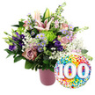 A radiant, carefully styled 100th-celebration display is set against a bright white background, evoking the feeling of a special family party in Mill Hill, perhaps after a leisurely walk along the nearby green spaces. On the left stands a contemporary cylindrical vase in a muted, matte pink, its fine ribbing adding gentle texture to the otherwise smooth surface. It holds an abundant bouquet, artfully rounded and densely filled, that showcases a sophisticated palette of pink, mauve, purple, lavender, lime green, and white. At the top and centre, light pink lilies bloom widely, their star-shaped petals framed by long stamens, while a few upright buds hint at more flowers to come. Clustered closely around these lilies are roses in soft blush and deeper dusty-rose tones, their velvety petals unfolding in rich layers. Nestled between them, velvety purple lisianthus blooms offer depth, and dainty lavender asters with sunny yellow centres bring a garden-fresh lightness, as if gathered from borders near Mill Hill Park. Bright lime green button chrysanthemums provide playful points of contrast with their tightly ruffled, spherical heads. Throughout the bouquet, fine sprigs of white baby's breath weave in and out, creating a soft, cloud-like haze that ties the colours together. Mixed dark green foliage, both broad and slender, frames the arrangement, giving it structure and a natural, flourishing look. To the lower right, slightly overlapping the bouquet, a shiny round foil balloon contributes a jubilant finishing touch. Its surface is densely speckled with multi-coloured confetti dots, while in the centre, large bold white numbers 100 stand out, enhanced by a subtle 3D effect. The overall scene conveys joy, longevity, and gratitude, perfectly suited to represent a 100th birthday or centenary anniversary bouquet available for same-day delivery around Mill Hill.