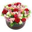 The image shows an opulent dome of roses rising from a round black hat box that is trimmed at the base with a slender ribbon of red, all framed by a clean white backdrop. The bouquet has been designed in a dense, rounded form so that the viewer sees an uninterrupted quilt of petals in varying stages of bloom. Deep, velvety red roses are scattered across the dome like jewels, intertwining with softer shades of blush and pale pink, their gentle tones softening the overall look. Cream and pure white roses bring brightness, while peaches and corals add a warm glow reminiscent of late afternoon light over the fields beyond Mill Hill. Pockets of vibrant fuchsia and the cooler, sophisticated notes of lavender and mauve roses contribute both contrast and elegance. Some blossoms are fully open, showcasing their swirling centres, while others remain partially closed, promising days of continued beauty after the arrangement is delivered to a Mill Hill home near the Ridgeway or close to Mill Hill Park. Tiny spray roses nestle between the larger blooms, and flashes of lively green foliage peek through, their fresh, glossy leaves giving the bouquet an airy lift. The hat box's matte black surface and neat proportions complement the fullness above, creating a design that feels both luxurious and contemporary, like a statement piece on a polished dining table along Mill Hill Broadway. With no extra decoration to distract from the flowers themselves, this photograph highlights the florist's expertise in colour blending and structural balance, evoking a perfect gift for anniversaries, birthdays, romantic gestures, or elegant thank-you moments across Mill Hill and nearby North London neighbourhoods.