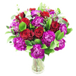 A sumptuous, rounded bouquet of deep red roses and magenta-purple carnations sits in a simple clear glass vase, captured against a crisp white background so every hue reads with clarity. The roses range from tight, velvety buds to gently unfurling blooms whose spiral centers and plush petals carry a soft, romantic perfume; alongside them, ruffled carnations in an intense fuchsia-leaning purple add lively texture and a modern, artistic edge. Bright, glossy green foliage-likely Italian ruscus-fills the base and frames each bloom with a polished sheen, while slender sprays of silvery eucalyptus lift the composition with a cool, delicate brightness and a faint herbal scent. The arrangement is densely packed, forming a luxurious dome of colour and form where leaves and petals overlap in a layered silhouette; light skims the petal tips and glass rim, giving the bouquet a quietly luminous quality that reads both fresh and celebratory. From a florist's perspective the stems are neatly visible through the transparent vase, communicating the arrangement's freshness and the careful mechanics beneath the bloom face-wire-like stems, clean cuts, and thoughtful spacing that ensure longevity and balance in the display. This is a design suited to an intimate anniversary table, a Valentine's Day declaration, or a proud occasion-weddings of small scale, milestone birthdays, or a heartfelt congratulations sent across Mill Hill. Imagined in the natural morning light of a Mill Hill kitchen or delivered to a neighbour on Mill Hill Broadway, the bouquet's colours feel warm and immediate, a tactile expression of affection and generosity delivered with local care.