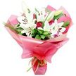 A beautifully balanced bouquet of white lilies and deep red roses appears against a crisp white background, every detail of the floristry clearly visible. Several large Oriental lilies form the focal point, their elegant, trumpet-shaped blooms fully open with smooth, pure white petals that curl slightly at the edges, revealing a cluster of dark brown anthers and a central pistil dusted lightly with pollen. A few elongated buds stand among them, wrapped in soft green with touches of cream, indicating fresh, unopened flowers that will extend the life and drama of the bouquet once it reaches a home in Mill Hill. Interlaced with the lilies are deep red roses, rich and velvety, some still tightly closed and others gently opening to reveal layered petals, suggesting quiet romance and affection. The blooms are supported by an abundance of dark green foliage, including broad, shiny leaves that catch the light and slender, grass-like strands that add motion and height, echoing the textured greenery you might notice while walking toward Mill Hill Broadway or through local parks. The stems are bound together and wrapped in bright pink, glossy cellophane or floral paper, folded into generous, undulating layers that surround the bouquet like a celebratory cloud. At the base, a slim lime green ribbon is tied firmly, its satin sheen and fresh colour creating a lively contrast with the pink wrapping and complementing the foliage above. The overall impression is of a thoughtful, uplifting bouquet, perfect for birthdays, anniversaries, or sending heartfelt congratulations to someone special in Mill Hill.