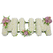 A lovingly crafted, three-dimensional funeral tribute spells the word 'MUM' in bold capital letters, each letter densely sheathed in a cloud of small, crisp white chrysanthemums that give the composition a soft, pillowy texture. The white surface reads as quiet and luminous - an emblem of purity and peaceful remembrance - while the tiny florets catch soft light to produce subtle highlights across the letter faces. Three small clusters of delicate pastel colour punctuate the purity: soft lavender roses and pale pink rosebuds tucked into the upper left arm of the first 'M', another cluster nestled in the gentle curve of the 'U', and a matching spray on the upper right arm of the final 'M'. Fresh green leaves and slender fern fronds weave between the roses, introducing cool, textured contrasts and a gentle botanical silhouette. A darker green structural base - likely ribbon-wrapped foam or moss over a hidden frame - is faintly visible beneath the blooms, giving the letters weight and definition without distracting from the floral surface.
As a Mill Hill florist would note, the arrangement reads as both personal and traditional: a quiet, tactile expression of love suitable for a funeral service, wake, or graveside memorial in familiar neighbourhoods like Mill Hill Village or beside the open lawns of Mill Hill Park. The scent is subtle and clean; the overall impression is one of careful handwork and calm dignity. Freshness and balance are evident in the placement of every blossom and leaf, creating a tribute that cradles memory in soft white and gentle pastels for a mother dearly missed.