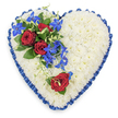 The photograph shows a large, heart-shaped floral arrangement designed for a funeral or memorial service, composed with a sense of calm precision and emotional depth. The heart's surface is entirely covered in a thick layer of small, pristine white chrysanthemums, their petals overlapping to create a continuous, velvety texture that feels gentle and soothing. The white flowers form a pure background that symbolises peace and remembrance. Encircling the entire heart is a generously wide royal blue satin ribbon, impeccably pleated so that soft ruffles rise and fall along the edge. The ribbon's deep blue colour and subtle shine bring definition to the shape, adding a formal, respectful frame that hints at the quiet dignity of services held around Mill Hill and its surrounding chapels. At the upper left curve of the heart, a bold cluster of flowers provides a focal point of colour. Three deep red roses, fully open and velvety, sit among dark green foliage, their rich crimson petals speaking of deep love and reflection. Weaving through and trailing from the roses are electric blue dendrobium orchids, their slender stems and star-shaped blooms giving a fresh, modern flair to the otherwise classic design. Light green curly tendrils and leaf tips extend from the spray, softening the transition from the focal cluster into the white chrysanthemum base. On the lower right side of the heart, a single red rose has been carefully placed, mirroring the intensity and sentiment of the main group while offering a quieter, solitary note of remembrance. The overall effect is one of heartfelt condolence and quiet beauty, an arrangement that could be delivered by Flowers Mill Hill to a local service or family home as a gentle, visual expression of sympathy and enduring love.