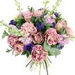 The bouquet in this image appears as a soft yet striking composition, carefully arranged against a pure white background that lets each colour and texture breathe. At its core, generous garden roses unfurl in shades of blush, antique pink, and dusty mauve, their spiralled petals creating a sense of classic, enduring romance. Intermingled are plush, ruffled carnations, their petals moving from creamy pale centres to deeper pink, fuchsia, and plum along the delicately frayed edges, adding a tactile, almost fabric-like richness. Cutting through the gentle pastels are accents of deep indigo-blue, seen in refined tulip-shaped blooms that lend depth, while a single open royal blue anemone with an inky, almost black centre anchors the front with dramatic contrast. Rising above and between the larger flowers, slender stems of lilac and pastel lavender stock carry clusters of small blossoms, introducing lightness, vertical lift, and the sense of a softly perfumed breeze, much like the air in Mill Hill's gardens after spring rain. Surrounding the flowers is an abundance of foliage: darker, glossy rose leaves and smooth, rounded eucalyptus in silvery green frame the bouquet with natural grace and suggest a cool, refreshing aroma. The stems are clearly tied at the base in a neat spiral, ready to slip into a vase in a home near Mill Hill Park or an apartment by Mill Hill Broadway station. Overall, the blend of pinks, purples, blues, and greens creates a soothing yet celebratory mood, making this bouquet ideal for intimate anniversaries, birthdays, new baby greetings, or a gentle message of support delivered locally in Mill Hill.
